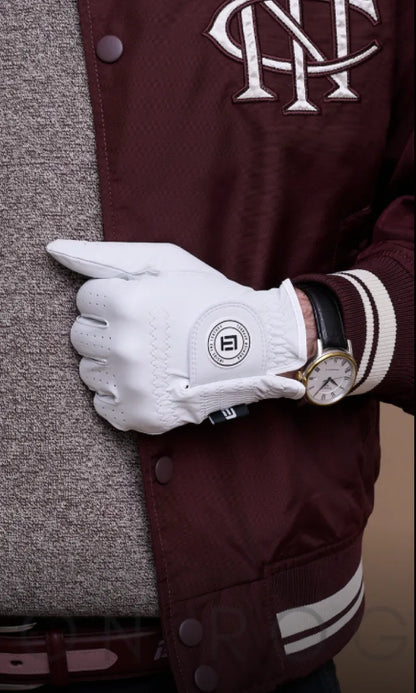 White golf glove held by a person wearing a maroon jacket with a logo.