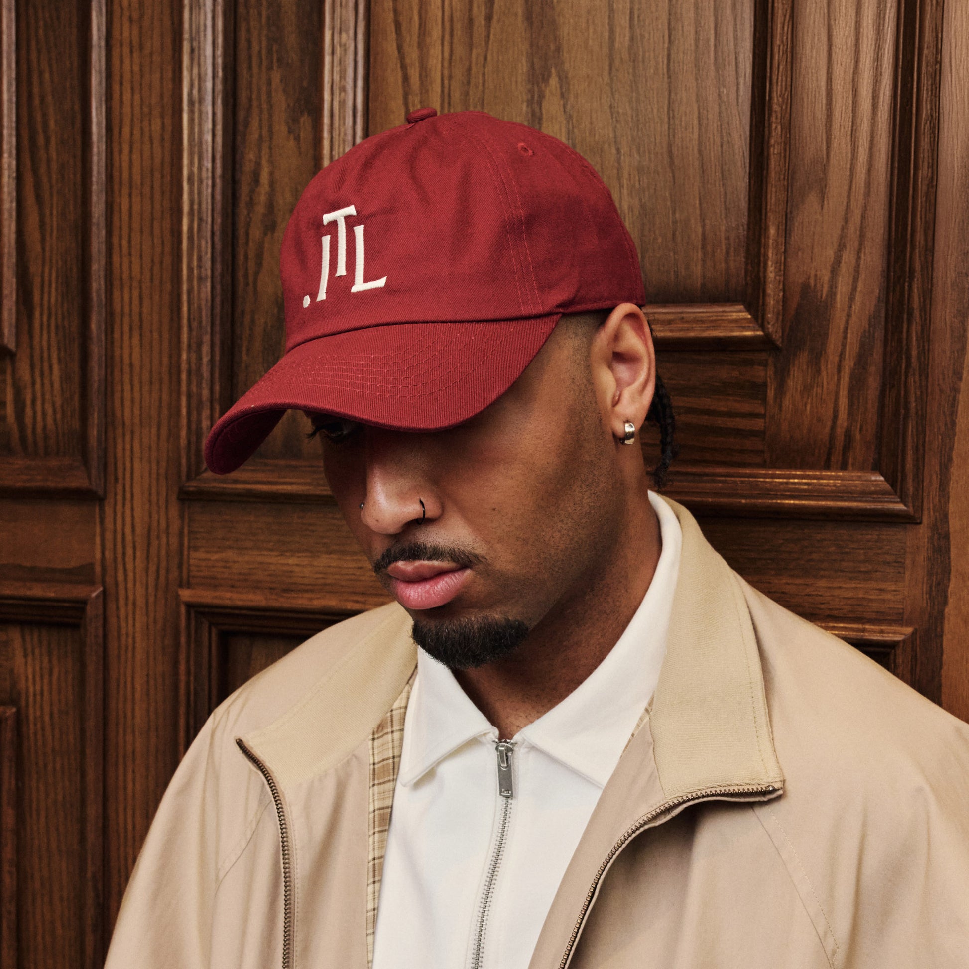 Man wearing a red cap with a logo against a wooden background