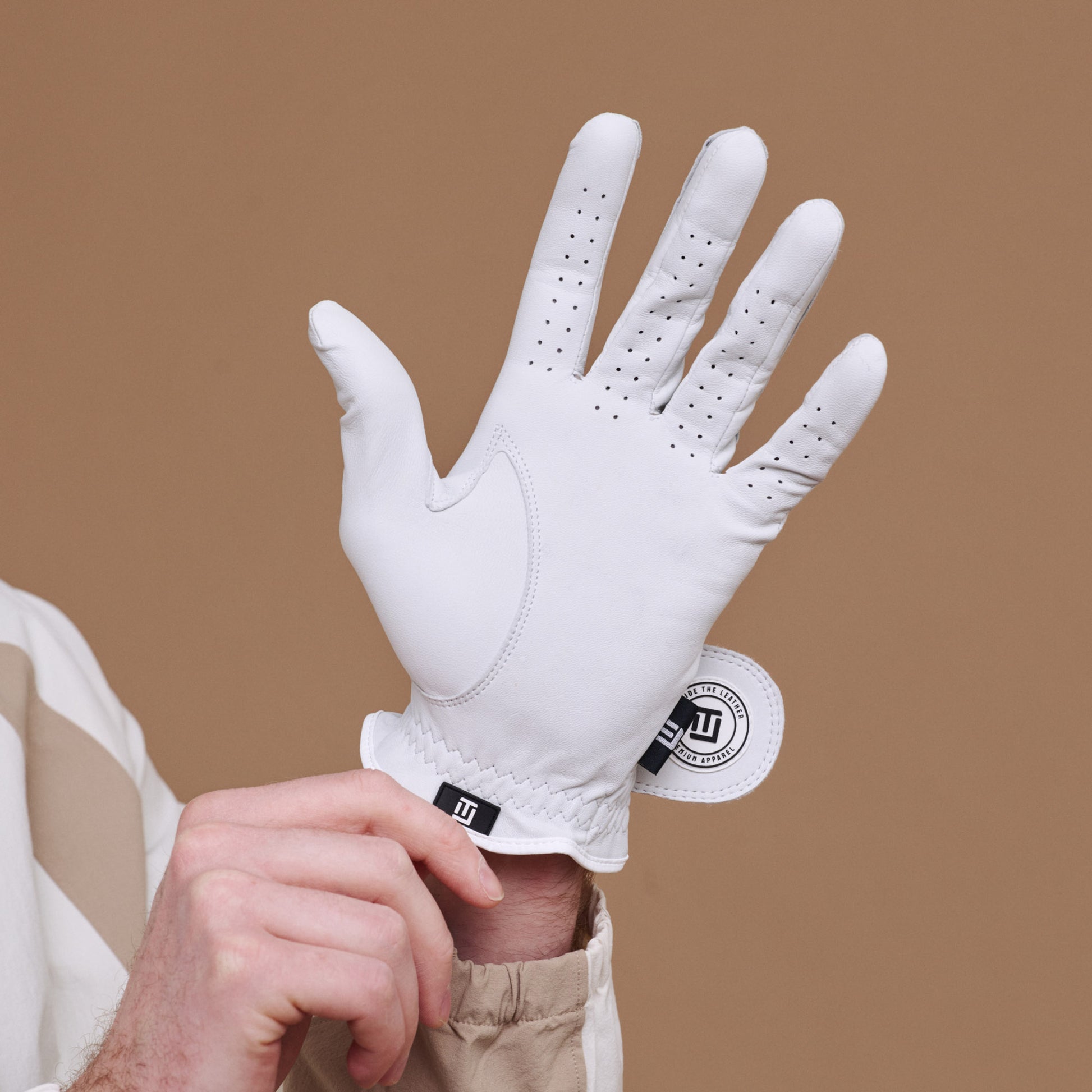 White golf glove with a brand logo on a brown background